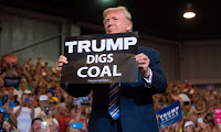 Donald Trump holds up a “Trump Digs Coal” sign as he arrives to speak during a Make America Great Again Rally at Big Sandy Superstore Arena in Huntington, West Virginia, August 3, 2017. (Photograph Credit: Saul Loeb/AFP/Getty Images) Click to Enlarge.