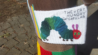 Close-up of a book cover image, rendered in crochet, of 'The Very Hungry Caterpillar' by Eric Carle