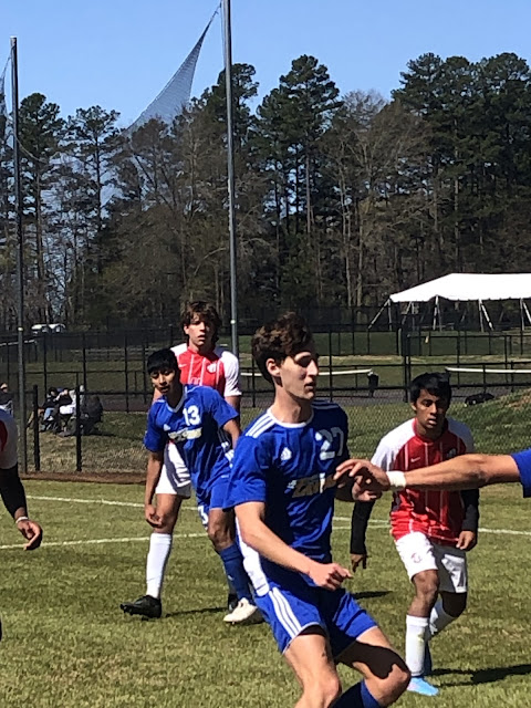 Josh by his goal at the back of a crowd of players watching a play unfold towards the sideline.