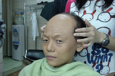 fake hair attach half of head to make it look like old man. More wrinkles added to the face 
