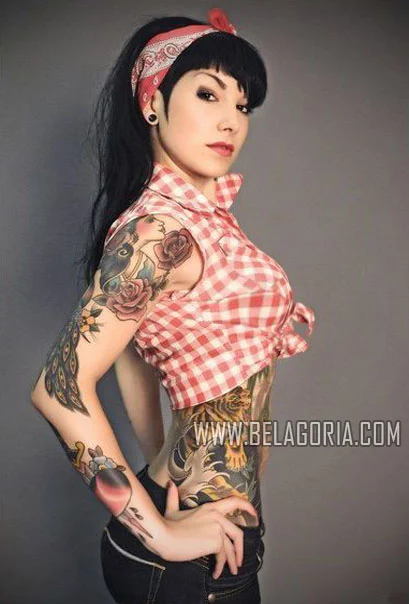 mujer de estilo rockabilly, con las manos en jarras, nos mira seductora, lleva tatuajes dold school