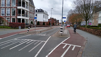 A street with a pair of bus stops right opposite each other with passenger areas floated with one way red cycle tracks on both sides. The road between the passenger areas is one vehicle wide.