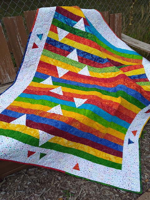 Quilt made of strips of bright colors, with inset accent triangles