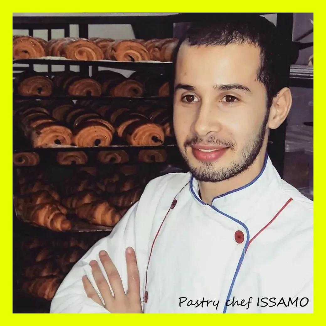 Pastry chef dressed in a white blouse with a smile, behind which cut the pastry