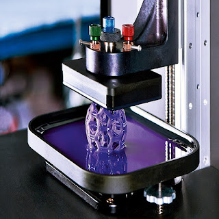 A person holding a tablet with 3D printing software and pointing at a 3D printer