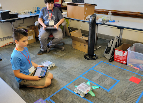 Students on the floor showing off a project that they learned how to code