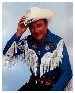 Portrait of Roy Rogers in cowboy costume smiling and tipping his white hat