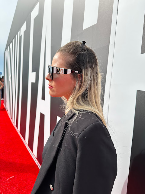 Debbie, woman in a black suit on a red carpet