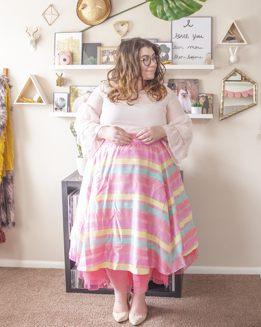 An outfit consisting of a light pink three tier ruffle sleeve blouse tucked into a pink, yellow and blue striped organza skirt with hot pink tulle and beige slingback heels.