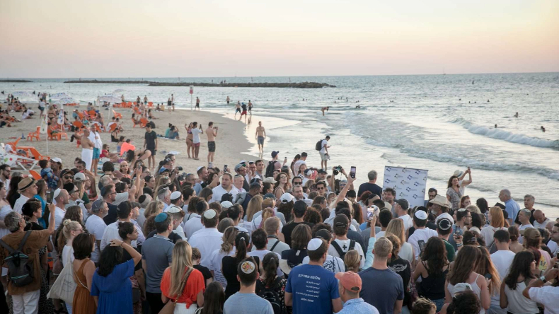 Judeus reunidos em oração à beira-mar em Tel Aviv, participando do ritual do Tashlich na tarde de Rosh Hashaná, o Ano Novo Judaico. Pedaços de pão ou pedras são lançados em um grande corpo de água natural como um ato simbólico para se purificar dos pecados do ano anterior e se tornar uma pessoa melhor no ano que vem | Foto por Miriam Alster/Flash90