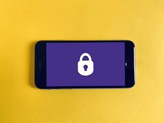 A black phone with a purple screen showing a lock icon. There is a yellow background.