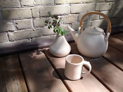 Image of a handmade ceramic country tea set including teapot mug and vase in summer