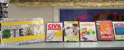 Countertop display of books arranged upright on stands, their titles facing outward. To the left, a handmade sign out of colorful letters against black-and-white patterned contact paper reads, 'Salute to S.T.E.A.M.' There are yellow borders, darker polka-dots against a lighter-yellow background, above and below the lettering of the sign. From left to right, the books on display are 'STEM Careers: Civil Engineer,' 'Careers if You Like the Arts,' 'STEM Careers: Chemist,' 'Design, Animate, and Create with Computer Graphics,' 'and STEM Careers: Software Engineer.'