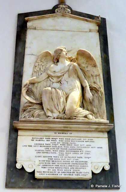 Wall-mounted memorial depicting a kneeling angel with outstretched wings, with inscription below