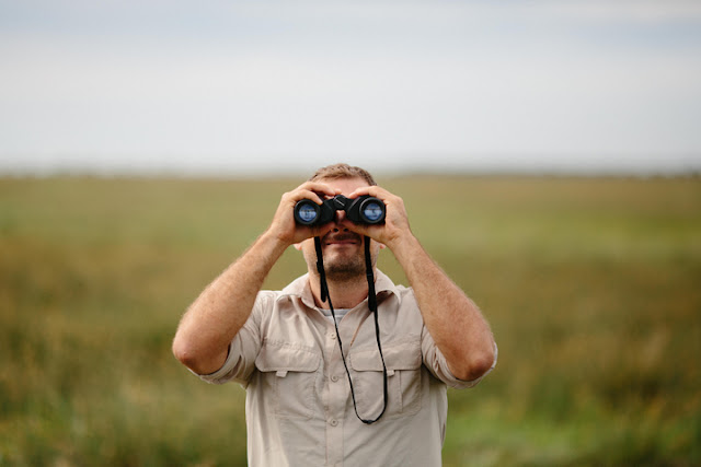 Hombre observando un campo con binoculares.