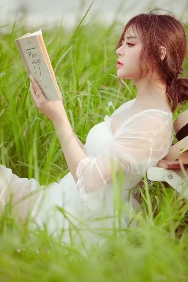 Thiếu nữ áo trắng ngồi đọc sách