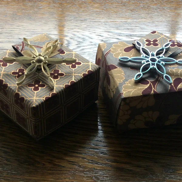 small handmade folded paper boxes with quilled snowflake gift toppers