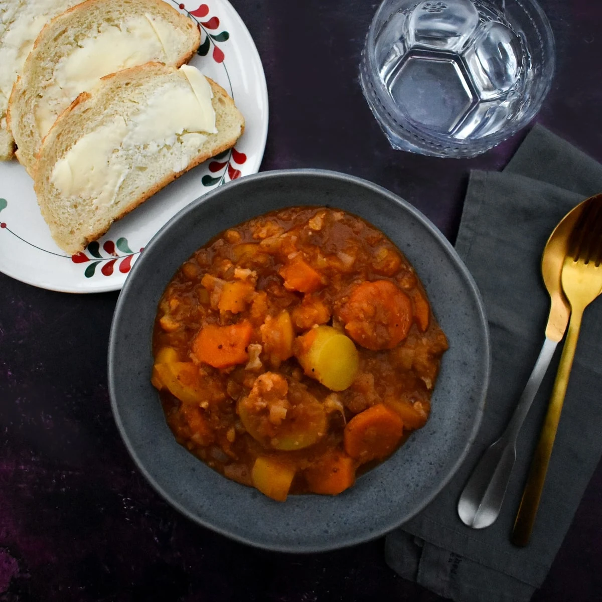 Butternut squash and lentil stew in a bowl served with buttered bread.