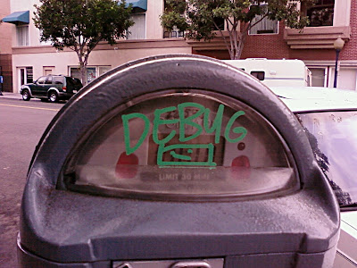A closeup view of the display window for a parking meter. In green writing is the word DEBUG in green maker and a simple below, probably a depiction of an audio cassette
