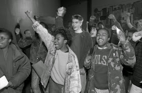 A black and white photograph of a group of smiling students with raised fists.