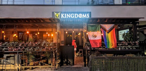 The face of 7 Kingdoms Bar lit up in the early mornings, with the flags of Mexico and LGBTQ+ communities