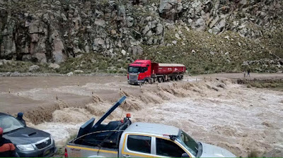 Caminhão tenta transpor uma ponte prejudicada pela elevação do nível das águas de um rio.