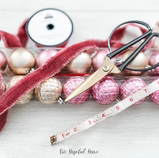 tubes of pink and gold Christmas ornaments velvet frayed ribbon scissors