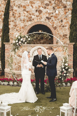 bride and groom standing at altar with white round arch