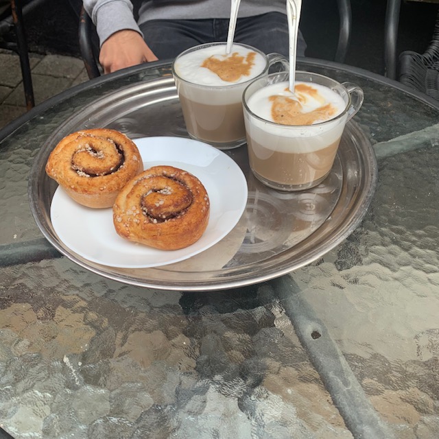 A tray with two large lattes and two cinnamon buns on a plate