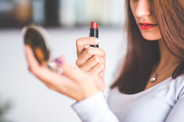 Woman applying lipstick in compact mirror