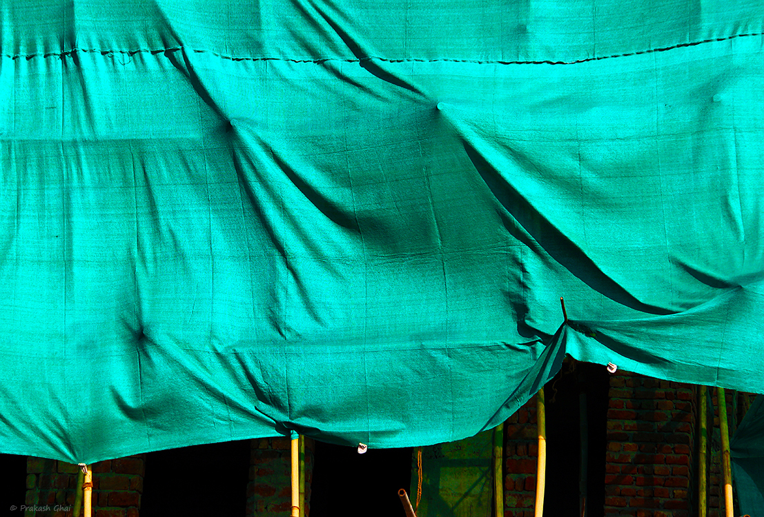 A minimalist photo of Building under construction covered by a green cloth.
