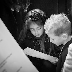 A girls shares her hymn sheets with a boy, photo is in black and white