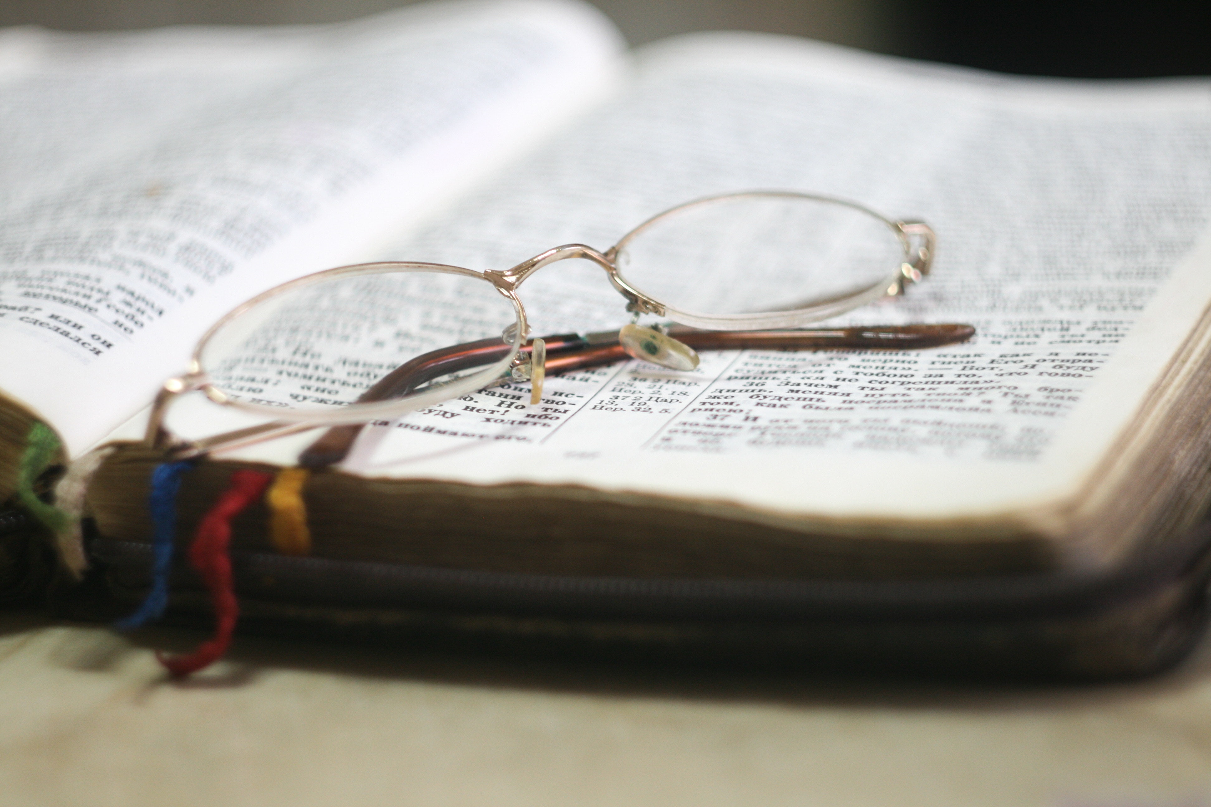 Eyeglass With Gold-colored Frames on Bible