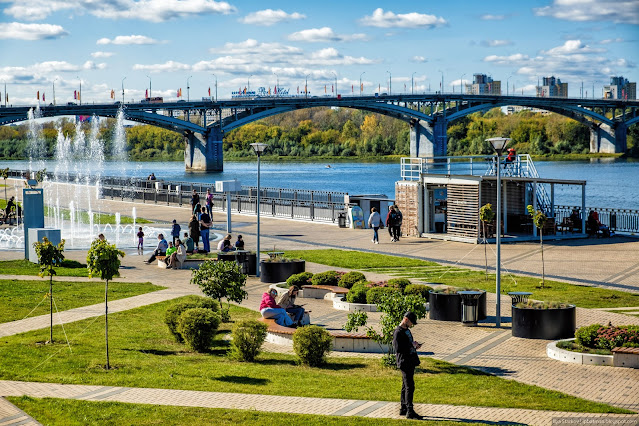 Люди отдыхают на набережной у реки в городе