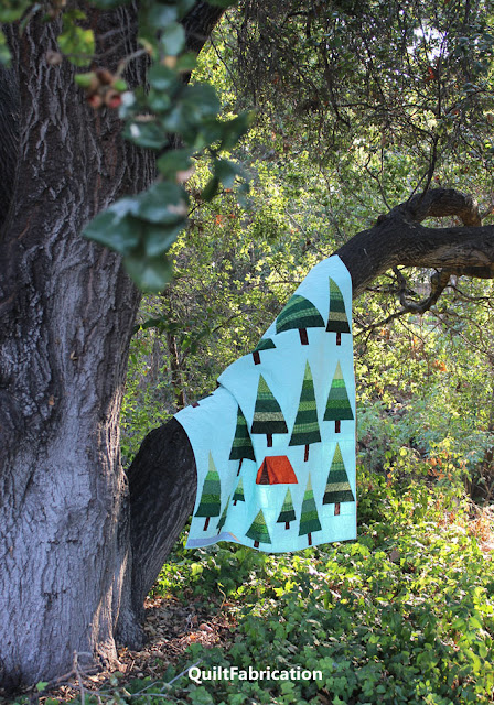 The Great Outdoors quilt by QuiltFabrication hanging from an oak tree limb