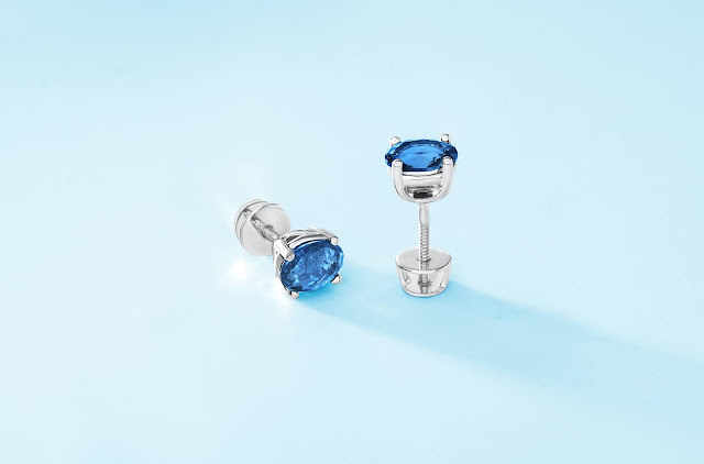 A pair of blue stud earrings resting on a light blue surface.