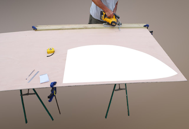 A full sheet of 9mm plywood is erected on trestles. A white shape shows the size of the layout by comparison.