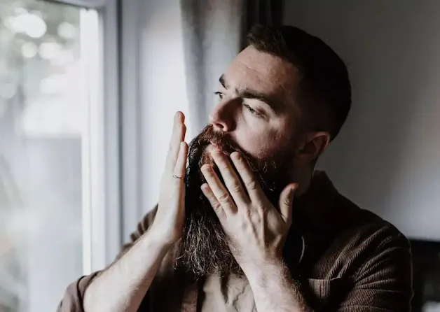 A man massages his long beard