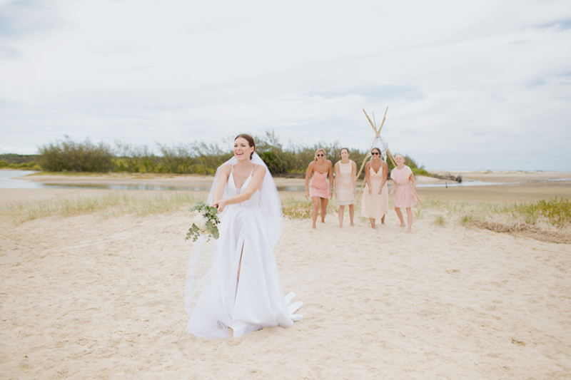 bride throwing bouquet on beach