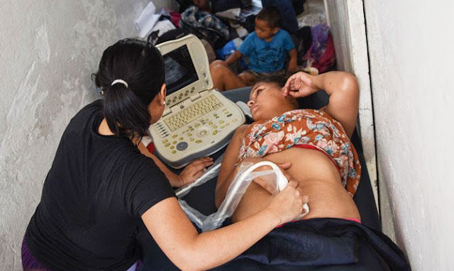 A Honduran migrant woman taking part in a caravan heading to the US, is having and ultrasound done to check his pregnancy, during a stop in their journey at the Central Park in Huixtla, Chiapas state, Mexico, on October 23, 2018. 