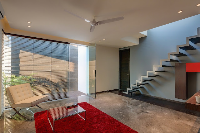 Picture of the entrance room with the staircase, red carpet and white chair