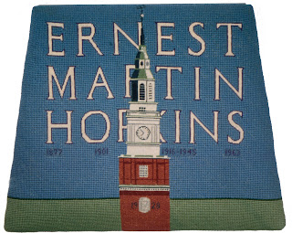 A needlepoint chair cover prominently featuring the name Ernest Martin Hopkins.