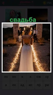 происходит церемония свадьбы на улице с освещением, невеста в платье идет