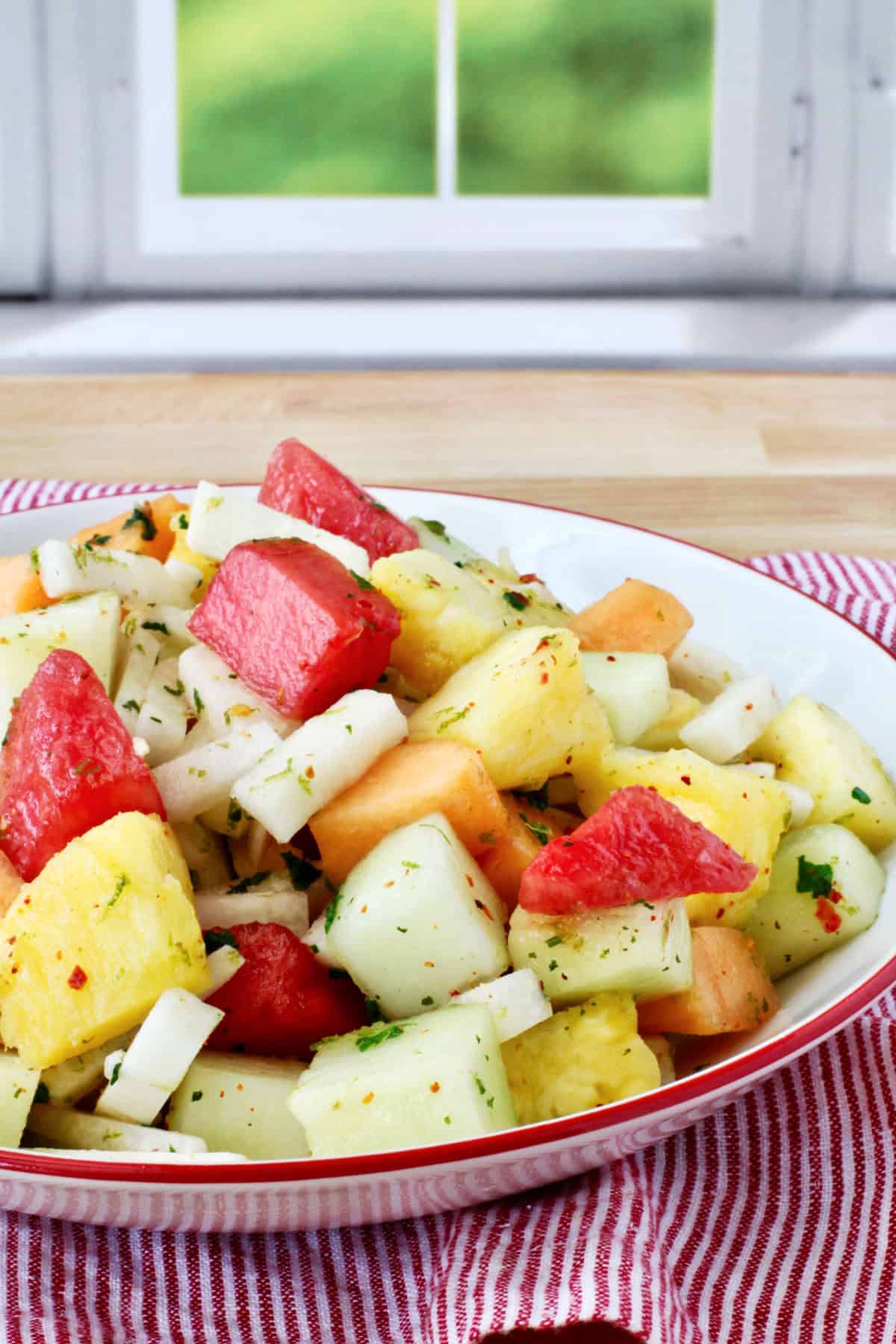 Melon, Jicama, and Pineapple Salad in a red-rimmed bowl.