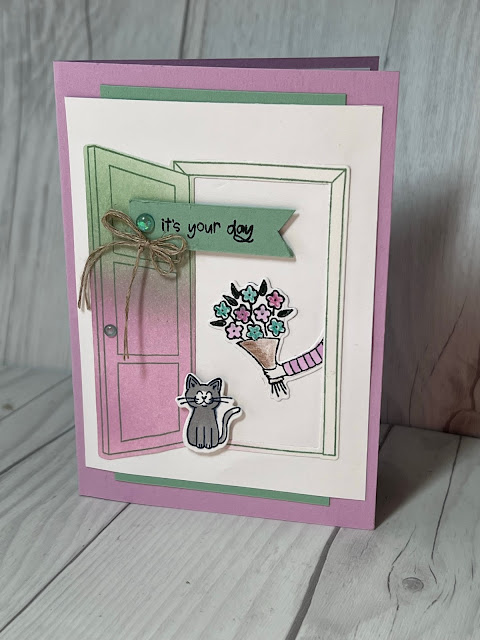 Greeting card for birthday with an arm holding a bouquet of flowers and a smiling cat