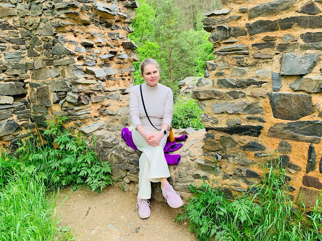 Linda sedí v okně zříceniny (Libštejn), před ní vyšlapaná cesta a bohatá vegetace... Za ní v průhledu okna jsou vidět stromy