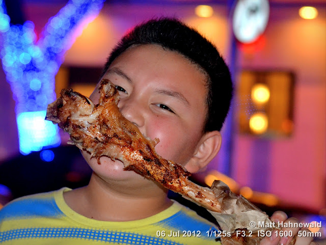 China, Beijing, Donghuamen night market, Chinese food delicacies, portrait, Chinese boy eating leg of lamb