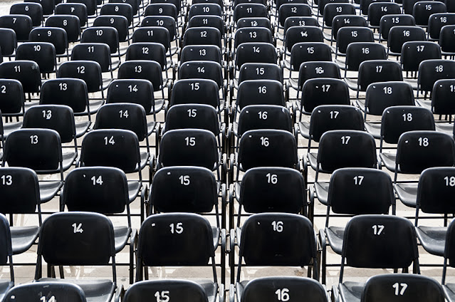 Filas de sillas numeradas de un auditorio vacío.