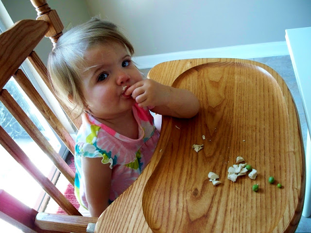 Eating peas and chicken in the highchair