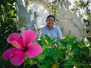 Sweet Smile Woman Traveler Sitting On White Carved Seat In The Beautiful Flower Garden At Tangguwisia Village North Bali Indonesia